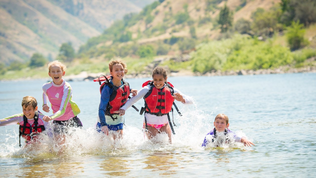 A group of kids on a family friendly rafting tour in Idaho playing on the Salmon river.