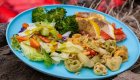 Fresh, colorful camp meal with salmon, pasta, and salad served outdoors during an Idaho wellness travel experience.