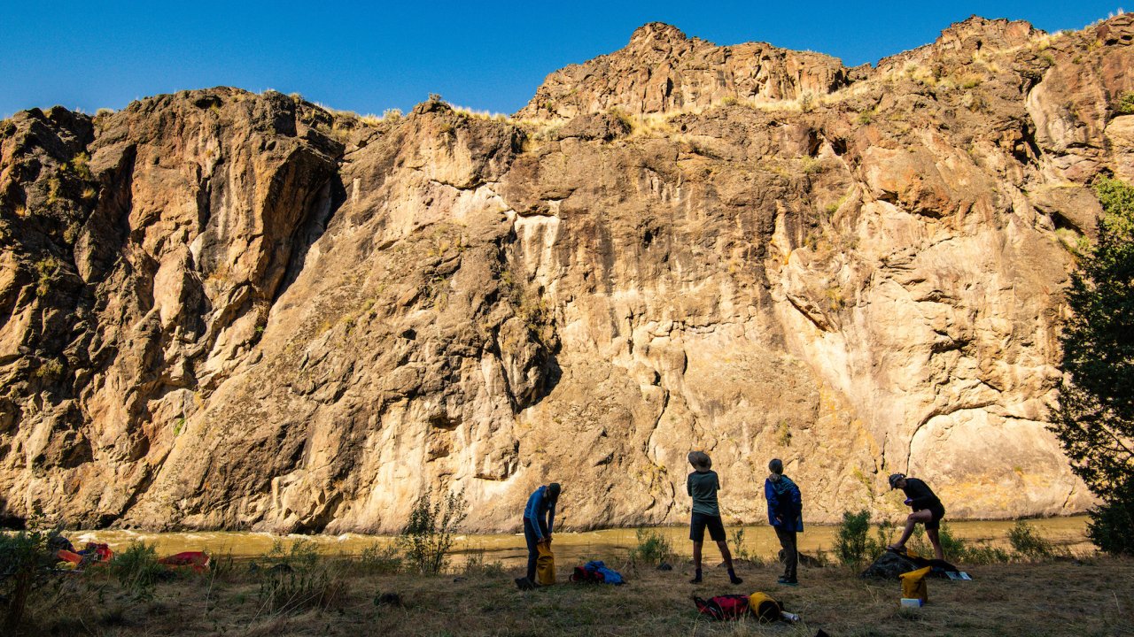 The shadow of four people stretching and getting ready for a day of rafting at sunrise