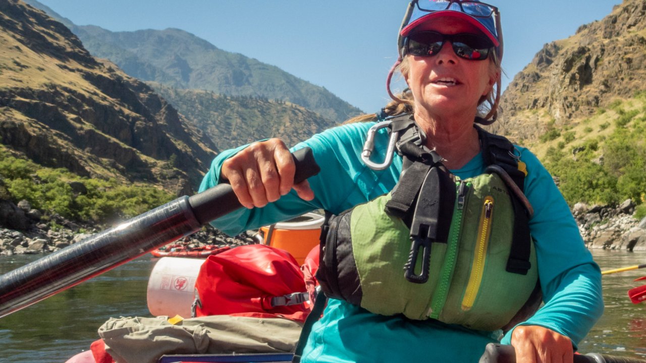 female guide rowing an oar raft