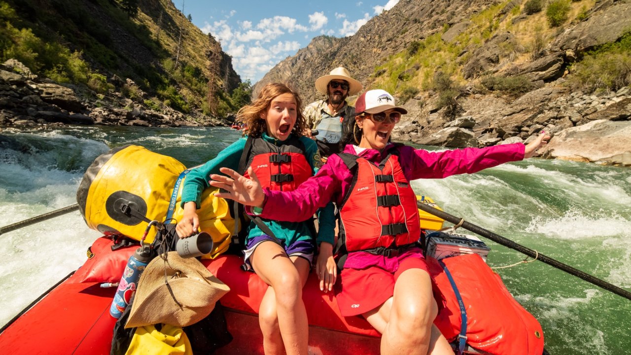 Excited mother and daughter riding whitewater rapids on the Middle Fork of the Salmon River during a guided Idaho rafting trip.