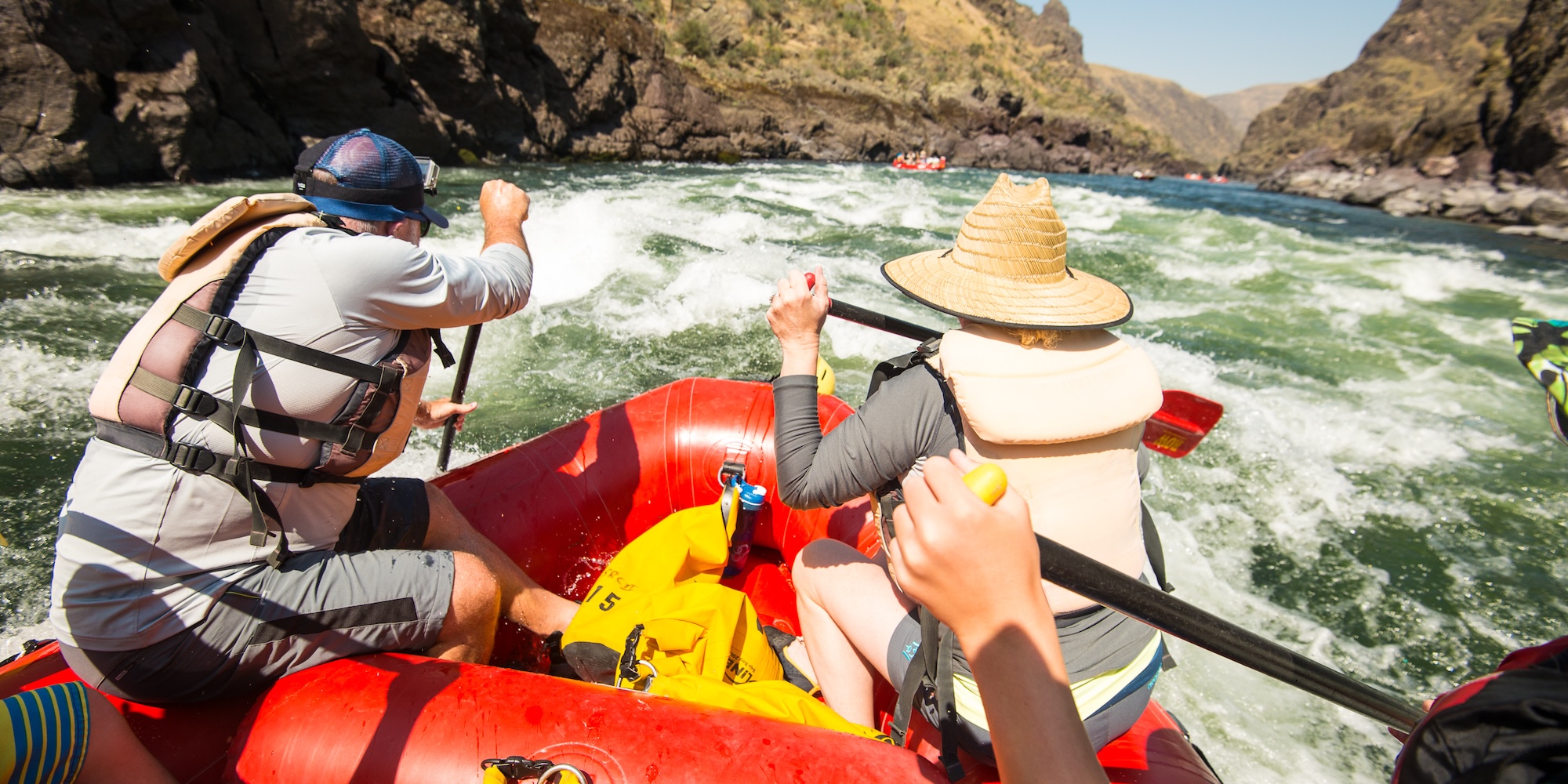 People in a raft navigating through a splashy whitewater rapid.