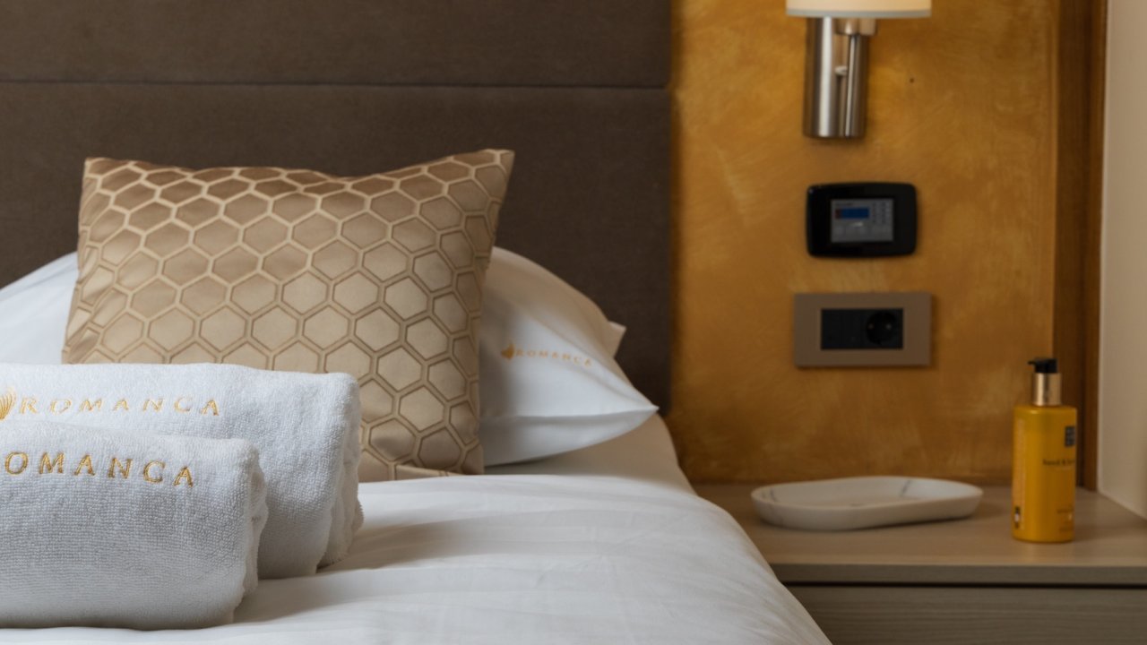 A yacht cabin bed with towels, pillows, and a bedside table.