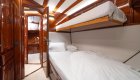 A yacht cabin with a bunk bed, wooden interior, an soft lighting.