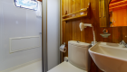 View of a small bathroom consisting of a sink, mirror, toilet, and shower on a small chartered cruise ship in Turkey